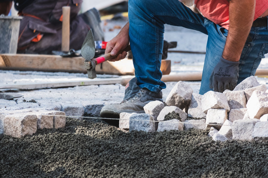 crew member kneeling down and installing pavers